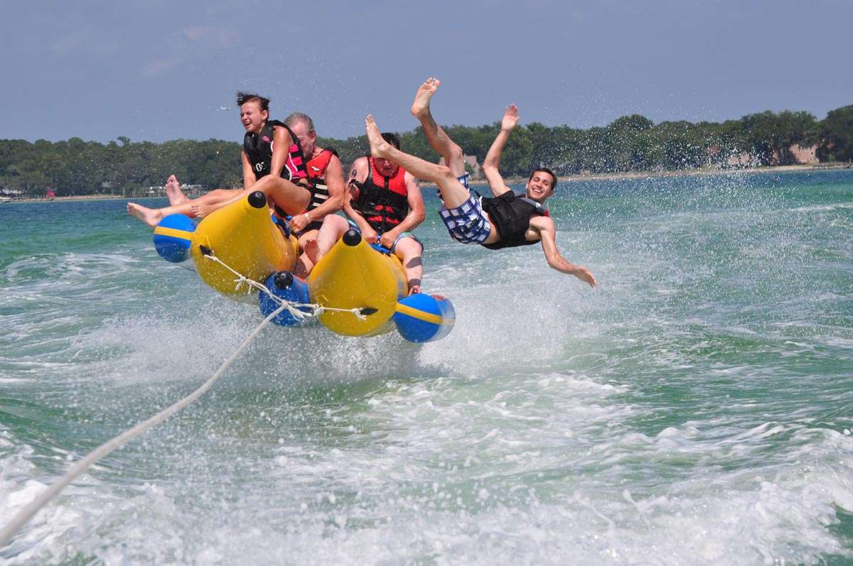People falling off an inflatable banana boat during a ride on the water.