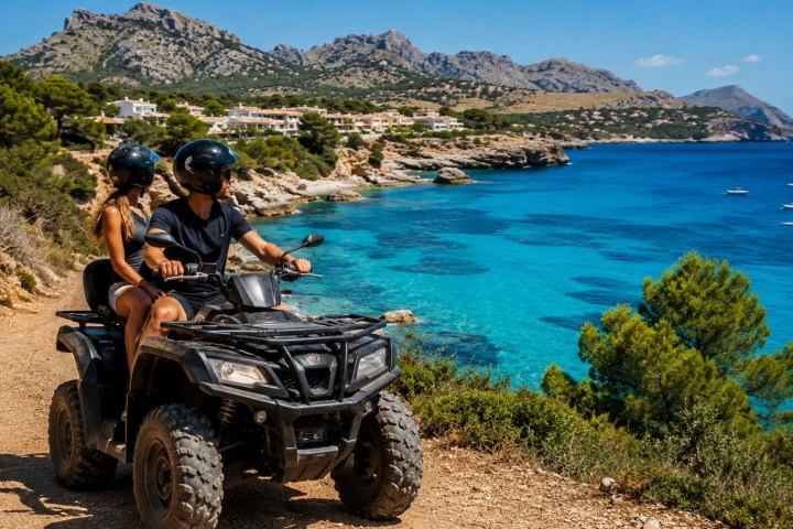 Couple on an ATV by the turquoise seaside with mountains in the background.
